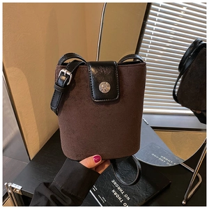 Detail of dark brown suede bucket bag with leather flap and silver buckle closure