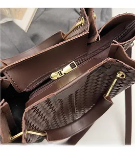 Detail view of smooth golden zipper and woven leather texture on a dark brown bucket bag