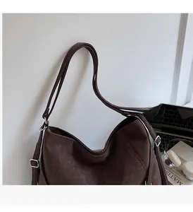 Detail of adjustable straps and stitching on a brown suede texture tote bag