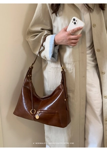 Detail of minimalist retro brown leather tote with golden buckle and adjustable strap