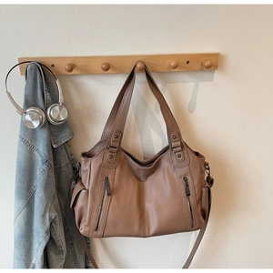 Detail view of brown pebbled PU leather tote with dual straps and side pocket detail