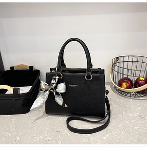 Detail of black lychee grain leather tote bag with printed silk scarf and gold branding