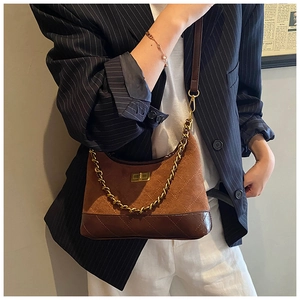 Detail view of the brown suede and leather patchwork crossbody bag with gold chain strap