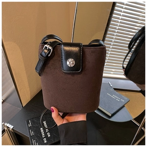 Detail of dark brown suede bucket bag with silver metal buckle and black leather strap