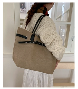 Detail of khaki canvas tote bag with black adjustable straps and metal eyelets