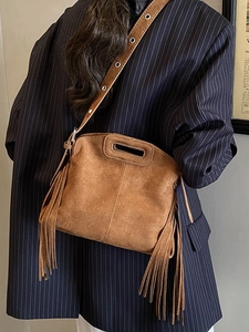 Vintage brown suede tote bag with long tassels and cutout handle shown on a model