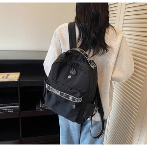 Detail view of the black nylon backpack showing the texture and the S.ICHAO lettered front pocket
