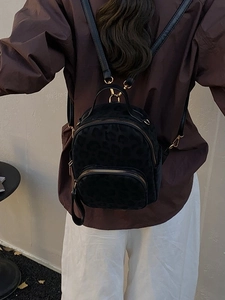 Mini leopard print backpack with gold zippers shown on a model in a street style setting