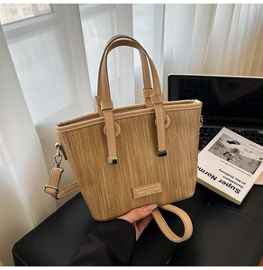 Detail showing the woven texture and fashion leather tag on a brown tote bag