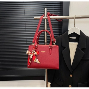 Detail of red lychee grain leather tote bag with printed silk scarf and gold branding