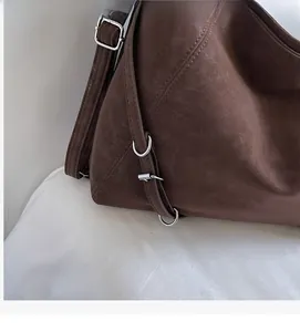 Detail of vintage brown suede shoulder bag showing metal hardware and retro texture