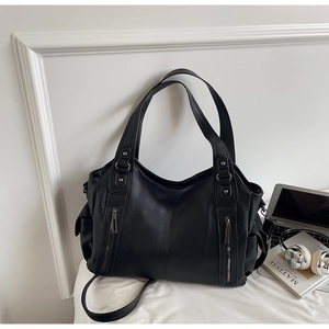 Macro detail of black litchi pattern leather tote bag with functional zippers and strap