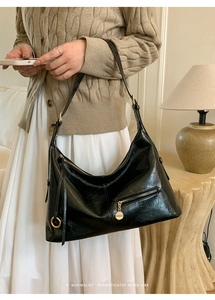 Detail of a vintage black hobo bag with oil-wax texture and golden hardware accents