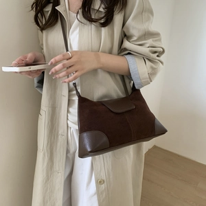 Detail view of retro brown frosted suede shoulder bag paired with beige trench coat