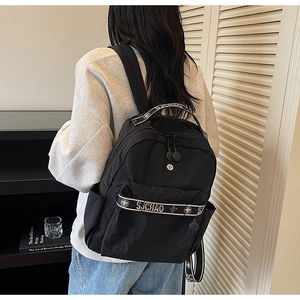 Detailed close-up of a black nylon backpack featuring Sichao brand straps and zipper pocket
