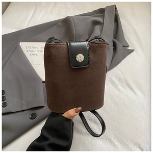 Close-up of brown suede bucket bag with black leather flap and silver buckle detail