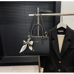 Detailed view of black litchi grain leather tote bag with elegant decorative silk scarf