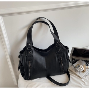Close-up of black lychee grain leather tote bag with vertical zippers and side pockets