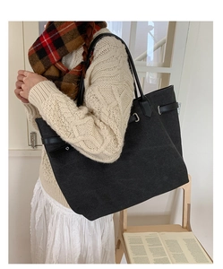 Detail of black canvas tote bag with leather straps and silver metal buckle on shoulder