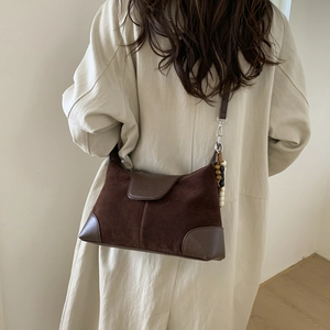 Detail of dark brown suede shoulder bag with beaded charm and leather patchwork