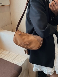 Brown suede crescent shoulder bag with vintage style worn with a black blazer jacket