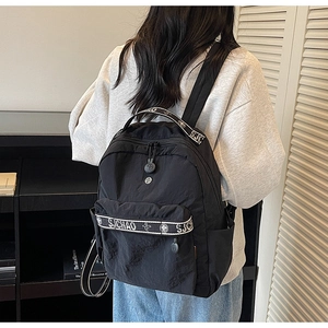 Detail of black nylon backpack with S.CHAO woven straps on model's back view