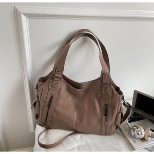 Detail of tan tote bag featuring pebble grain texture and metallic zipper accents