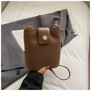 Detailed view of brown suede bucket bag with smooth leather strap and metal buckle