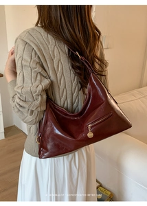 Close-up of retro burgundy tote bag in shiny leather with minimalist gold zip and charm