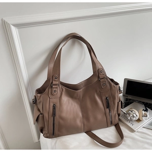 Detail of dark brown tote bag with litchi grain texture and decorative zippers