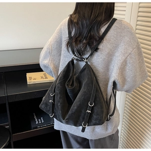 Detail view of large black tote bag with silver buckles and soft leather texture