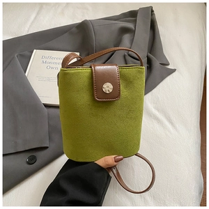 Close-up of green nubuck bucket bag with brown leather strap and silver metal buckle