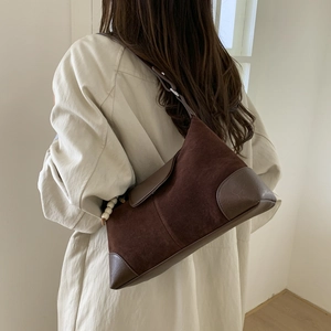 Detail of vintage brown suede shoulder bag with bead pendant and leather strap