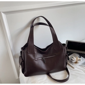 Detail of dark brown tote bag with pebble leather texture and functional front zipper