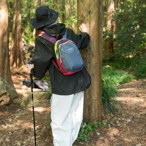 Detail of color-block hiking backpack with side mesh pockets in a forest setting