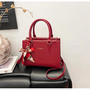 Detail of red leather tote bag with gold branding and floral silk scarf accessory