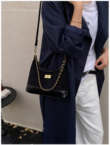Detail of black quilted crossbody bag with golden twist lock and adjustable chain strap