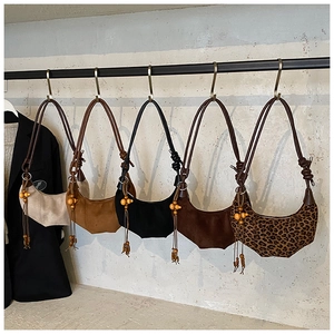 Collection of five suede crescent bags with woven straps and ethnic wooden bead tassels