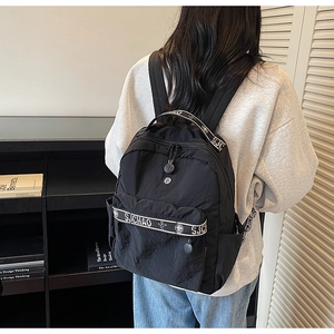 Close-up of black nylon backpack featuring branded SJ CHAO clover webbing and side pocket