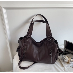 Detail of coffee brown tote bag with metal zippers, pebbled leather and work lifestyle props