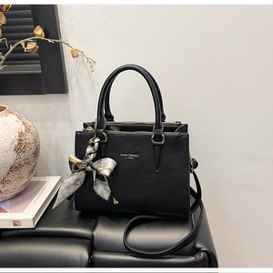 Detail of black pebbled leather tote with gold logo and decorative silk scarf wrap