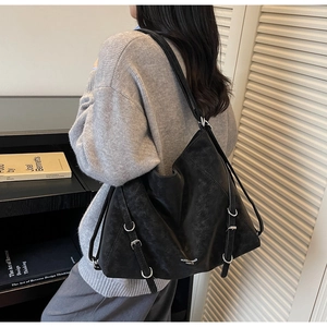 Detail of black leather tote bag with silver buckle and logo on a shoulder-worn model