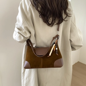 Detail of vintage brown suede crossbody bag with decorative wooden beads on a model