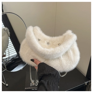 Vue détaillée du sac en fausse fourrure blanche avec breloques en forme d'étoile et cœur