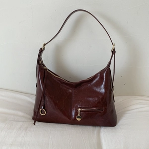 Detailed view of dark red vintage faux leather crossbody bag with golden zipper and ring charm