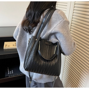 Detail shot of black woven leather bucket bag texture with gold hardware connectors