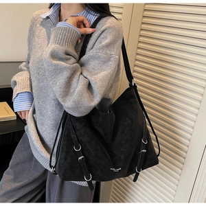 Detailed view of black vintage tote bag featuring silver buckles and matte finish texture
