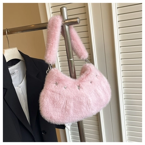 Détail du sac à main en fausse fourrure rose avec breloques étoiles et poignée en peluche