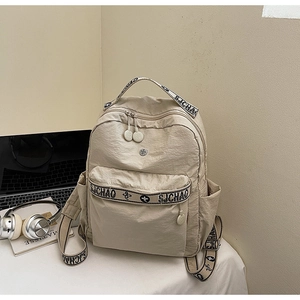 Detail of beige backpack featuring SJCHAO jacquard straps and textured nylon fabric