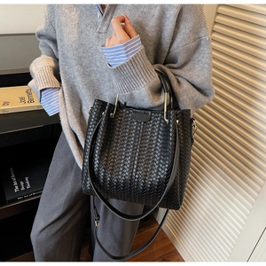 Close-up of black woven leather bucket bag with metallic handles and premium textures